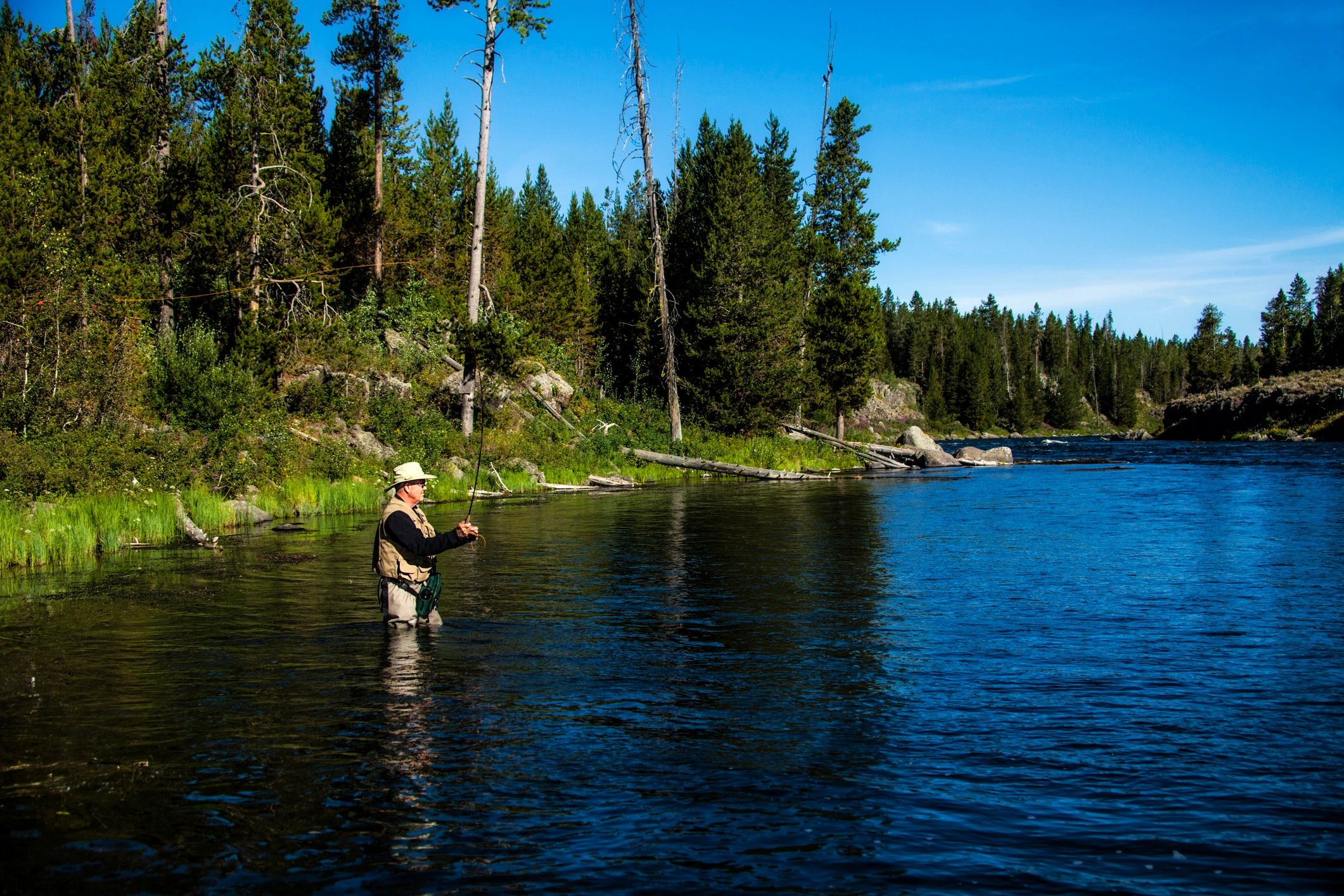 Fly fisherman casting into a pristine river